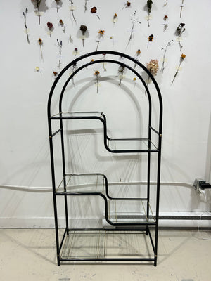 Black arched metal shelf with golden brass accents
