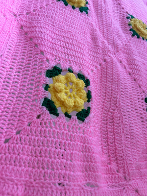 Pink hand knitted blanket with yellow crochet flowers