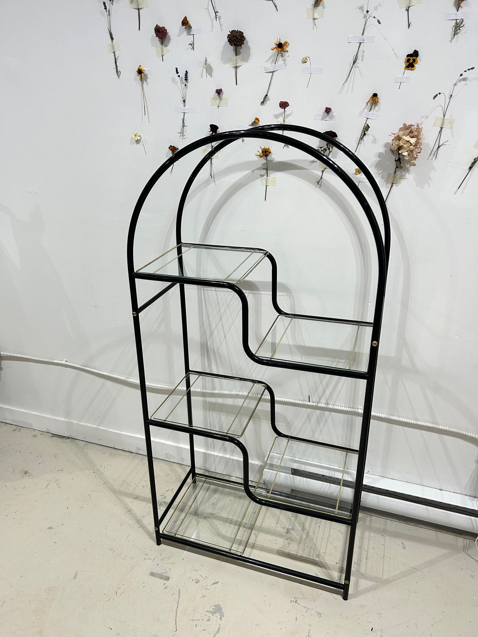 Black arched metal shelf with golden brass accents