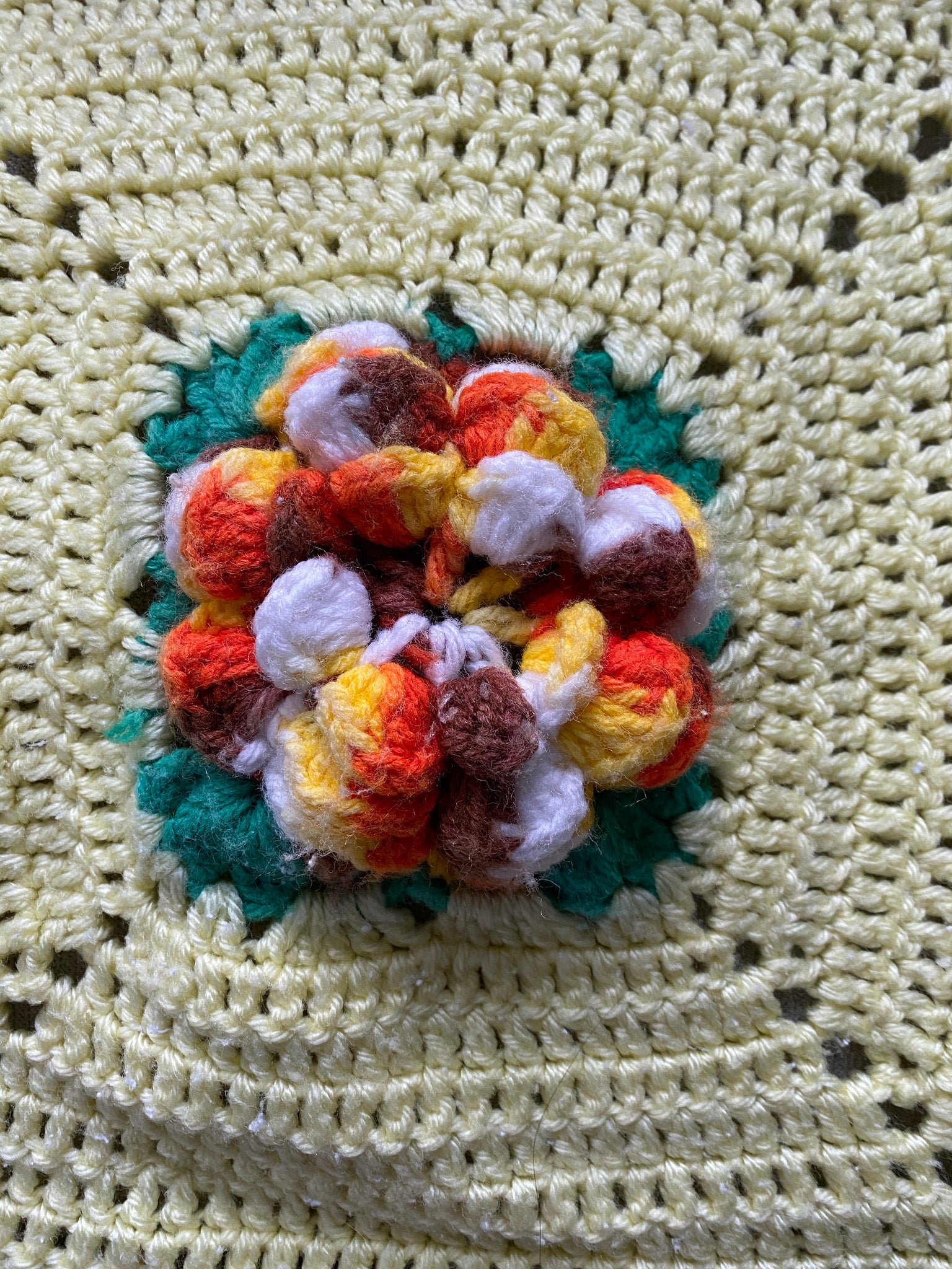 Yellow hand knitted blanket with crochet flowers